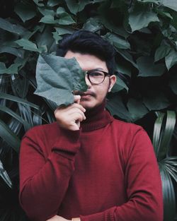 Portrait of young man holding leaf