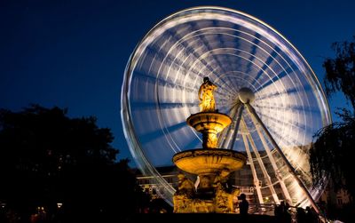 Low angle view of blurred ferris wheel against blue sky