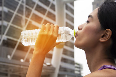 Young woman wearing tank top drinking water