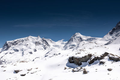 Scenic view of snow covered mountains against blue sky