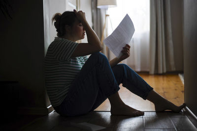 Side view of woman sitting on sofa at home