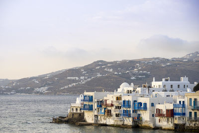 Buildings by sea against sky