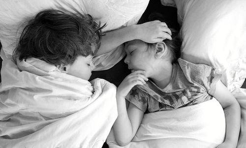 High angle view of siblings on bed