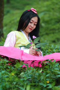 Young woman looking at pink flowering plants