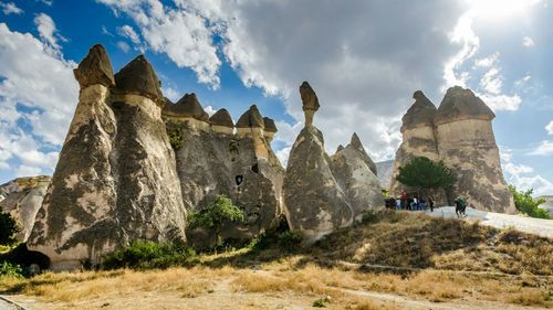 People standing on mountain against cloudy sky