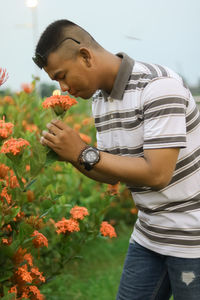 Young man smelling flower in field