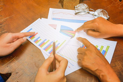 Cropped image of people discussing over graphs on table
