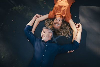 Happy mature man and woman lying on trampoline