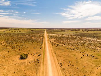 Scenic view of road amidst field against sky