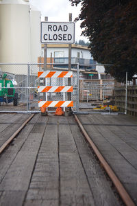 Information sign on railroad track in city against sky