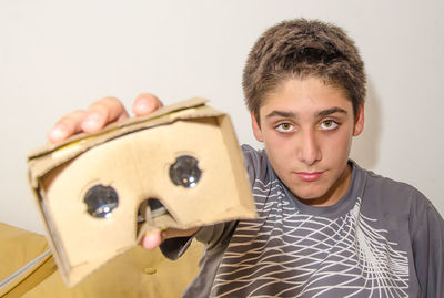 Portrait of boy showing cardboard virtual reality simulator attached to smart phone