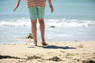 Low section of man standing on beach