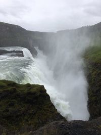 Scenic view of waterfall against sky