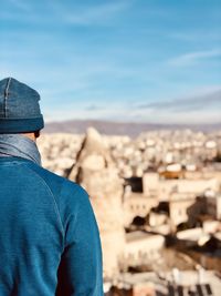 Rear view of man standing against blue sky