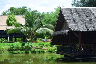 House by lake and trees against sky