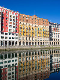 Reflection of building in canal against blue sky