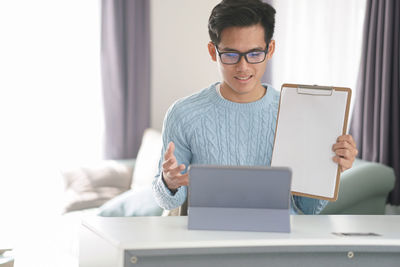 Young woman using mobile phone while sitting on table