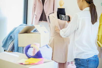 Midsection of female fashion designer photographing dress on mannequin in office