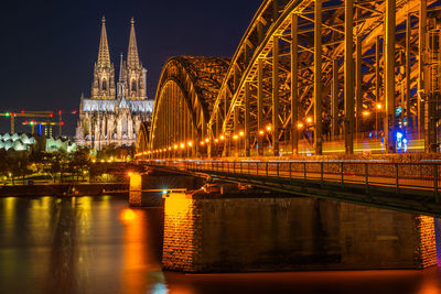 Illuminated bridge over river at night