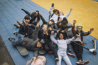 Portrait of school students with hand raised having fun at sports court