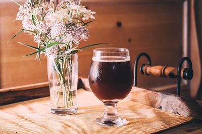Close-up of beer by flower on table