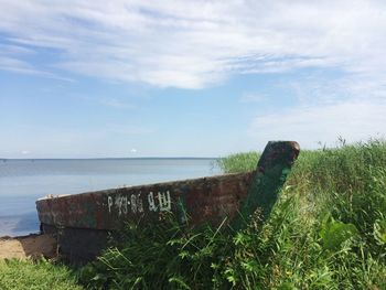 Abandoned boat by sea against sky