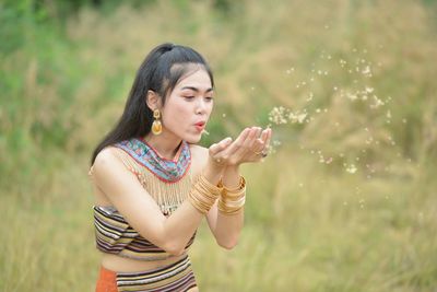 Young woman looking away while standing on field