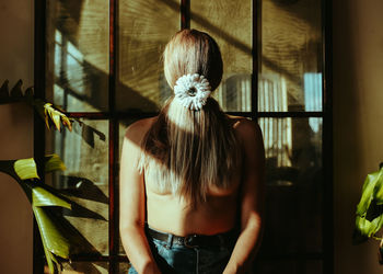 Rear view of woman standing by window at home