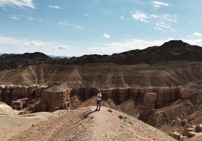 Man standing on rock against sky