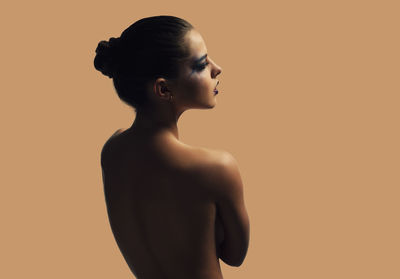 Close-up of shirtless woman against beige background