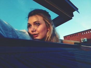 Low angle view of beautiful woman looking through skylight on roof