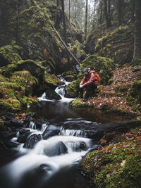 Hiker sitting by stream in forest