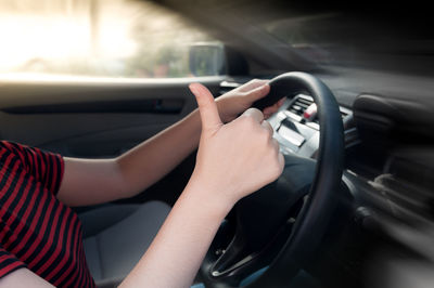 Midsection of woman gesturing while driving car