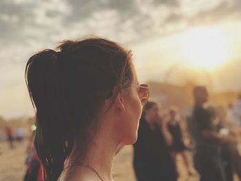 Side view of mid adult woman wearing sunglasses against sky during sunset