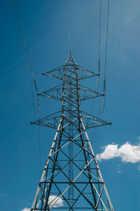 Low angle view of electricity pylon against blue sky