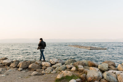 Rear view of man looking at sea against sky