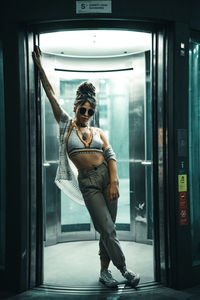 Full length portrait of young man standing against elevator