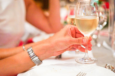 Midsection of woman holding drink on table at restaurant