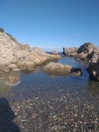 Rocks on beach against clear blue sky
