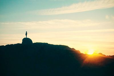 Silhouette woman standing on cliff against sky during sunset