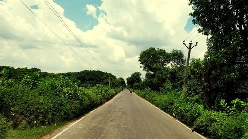 Empty road amidst trees against sky