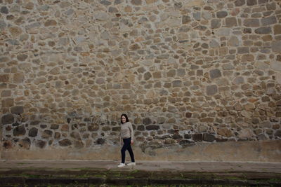 Full length of woman walking by wall