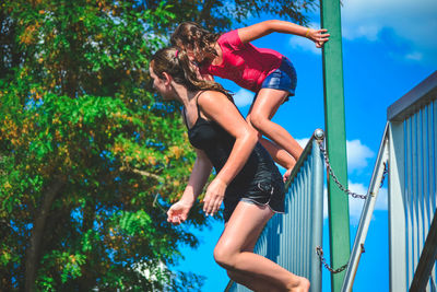 Low angle view of girl jumping against trees