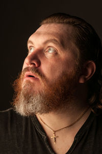 Close-up portrait of man wearing hat against black background