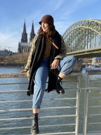 Woman with umbrella against railing in city