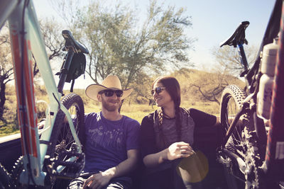 Happy male and female friends sitting in pick-up truck during summer