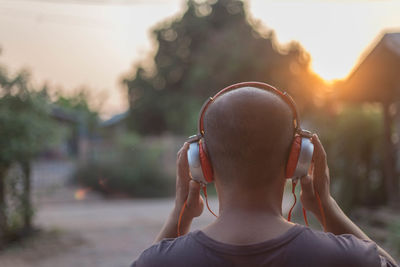 Rear view of man listening music over headphones