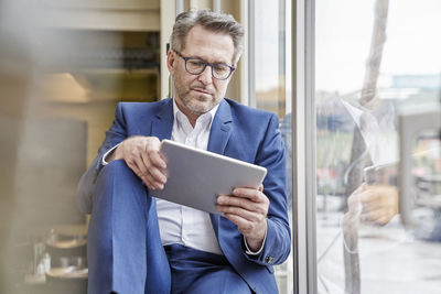 Mature businessman using tablet at the window