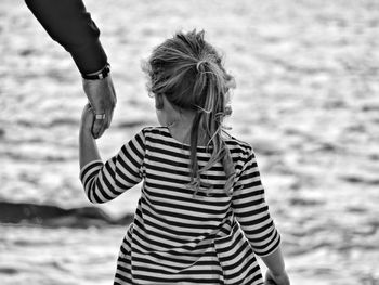 Rear view of father and daughter with holding hands at beach