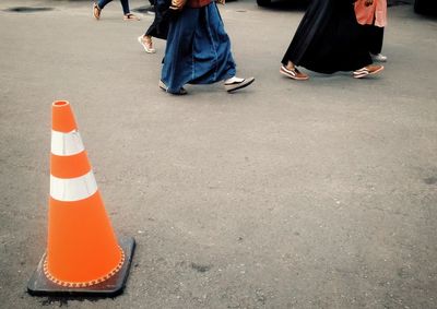 Low section of people walking by traffic cone on road